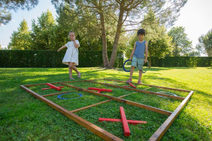 deux enfants jouent au jeu du morpion géant dans l'herbe aux Jardins de Colette
