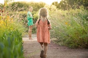 deux jeunes filles se promènent entre des parterres fleuris des Jardins de Colette