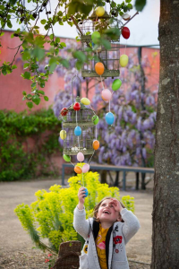 une filette essaie d'attraper une guirlande d'œuf accrochée à un arbre lors de l'animation de Pâques des Jardins de Colette