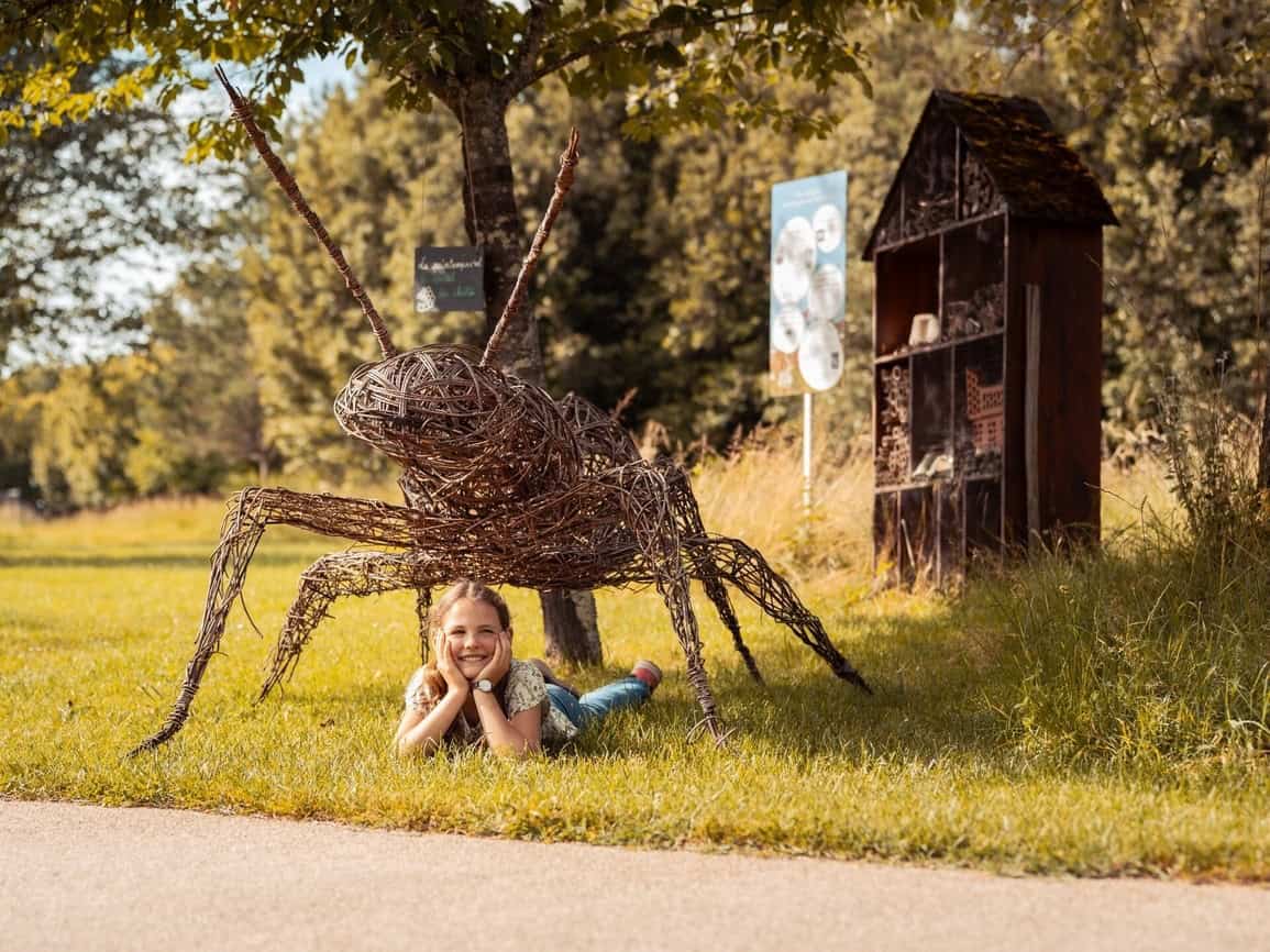 Jeune fille allongée sous un insecte géant aux Jardins de Colette